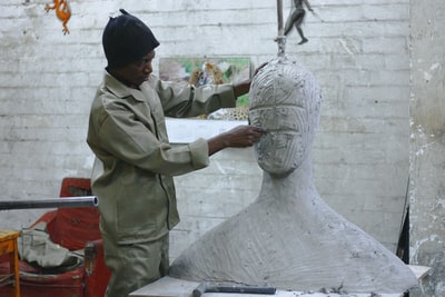 一个雕塑家在他的工作室里雕刻一个巨大的白色身体和头部